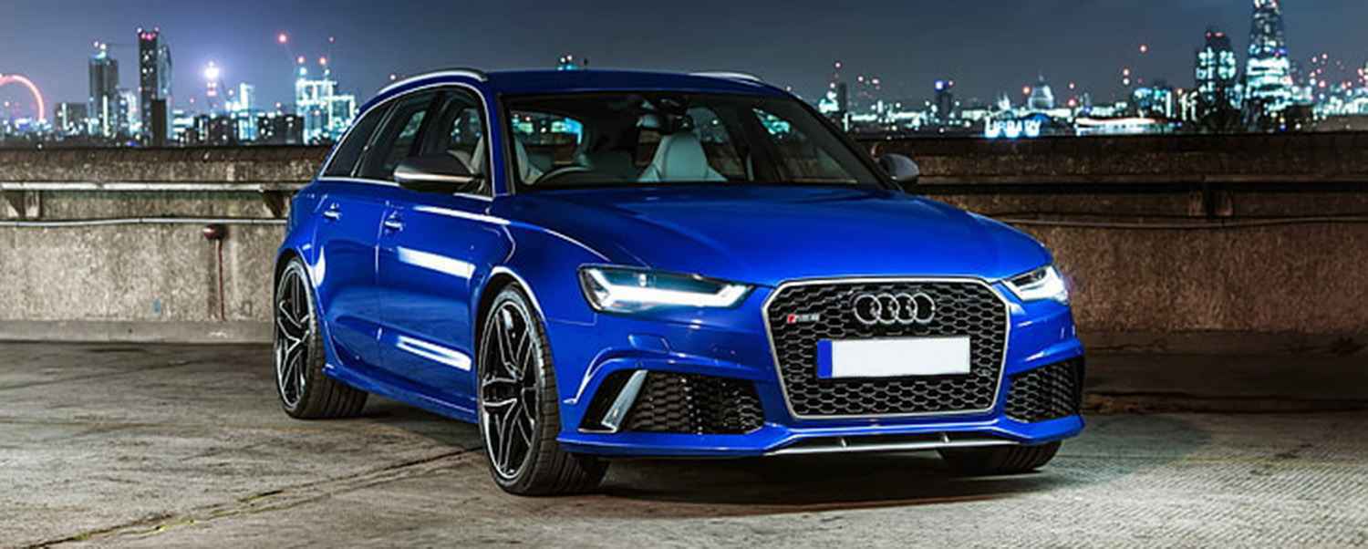 Blue Audi with dipped headlights illuminated at night