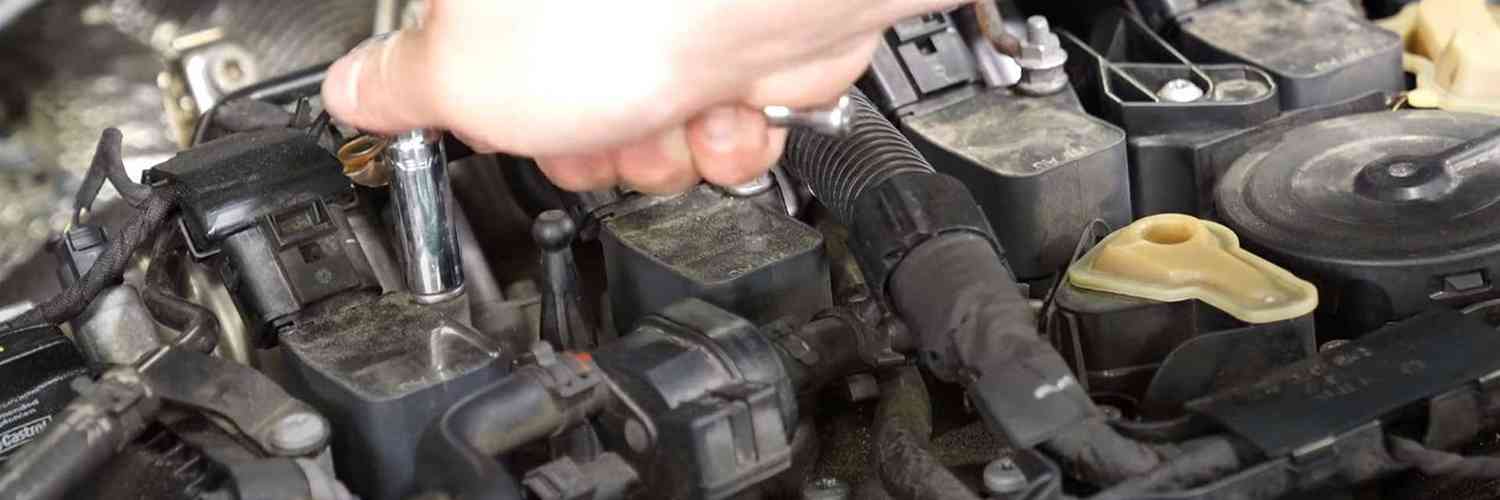 Tool working at an ignition coil mounting point in an engine bay