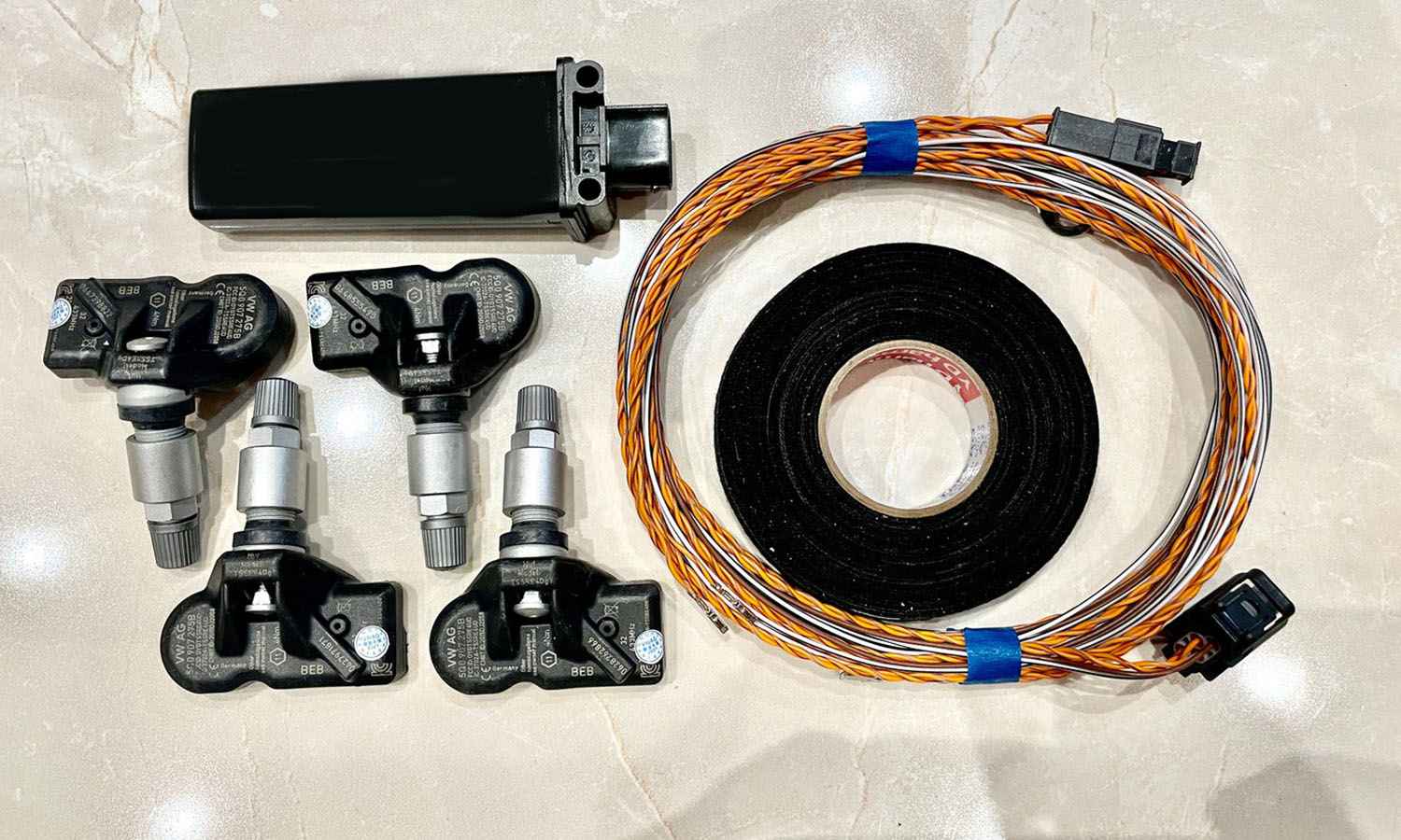 Four tyre pressure sensors beside a control unit and wiring harness