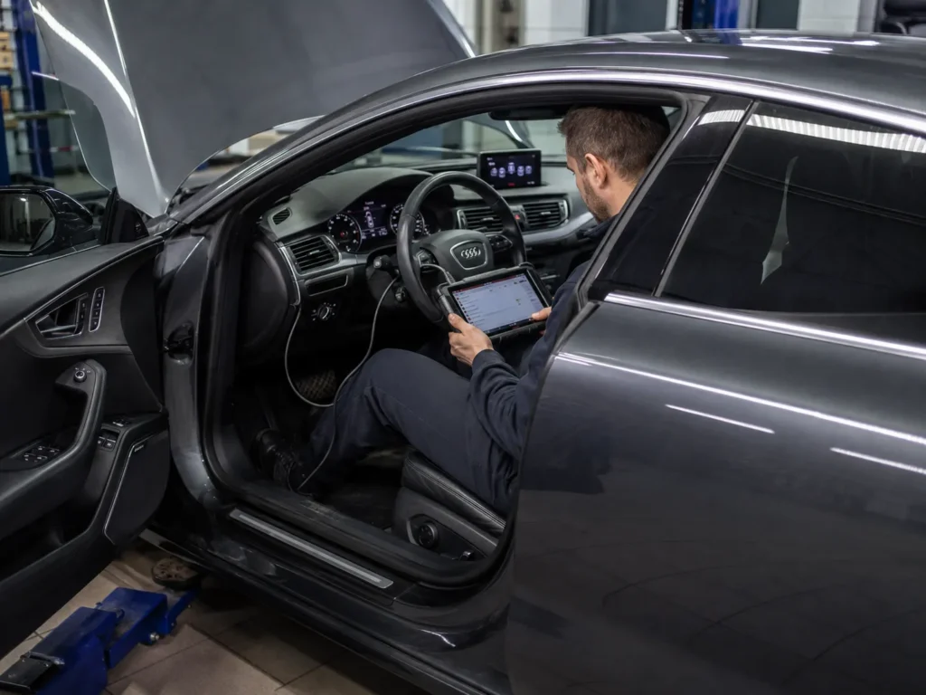 Mechanic performing a full diagnostic scan on a used Audi A7 during a pre-purchase inspection