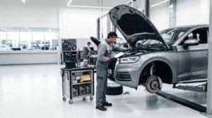 Audi master technician performing a comprehensive scheduled maintenance inspection on a lifted metallic grey Audi Q5 with the engine bay open and key service components prepared inside a premium Dubai service center.